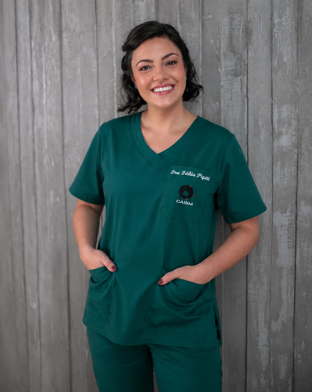 Dra. Fábia Pigatti smiling in green surgical scrubs on her endometriosis surgery service page